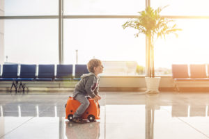 Kid rolling on luggage in airport