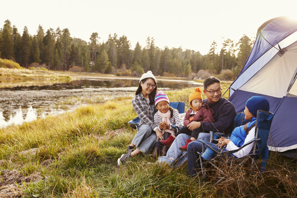 family on a camping trip relax outside their tent